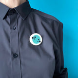 Teal Nabu brooch worn on a plain black shirt