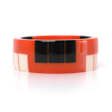 geometric bracelet cuff cast in orange resin, inlaid with black and white stripes