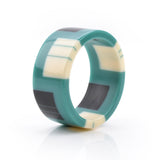 geometric bracelet cuff cast in teal resin, inlaid with black and white stripes