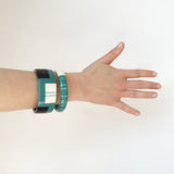 2 geometric statement cuff bracelets worn on model's arm, holding a bunch of flowers